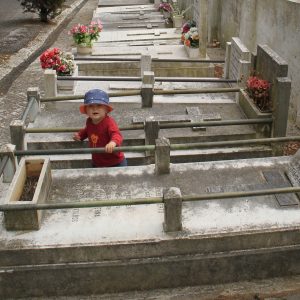 Kleines Kind zwischen Gräbern auf einem Friedhof