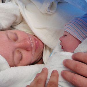 Neugeborenes in den Armen der Mutter im Kreißsaal